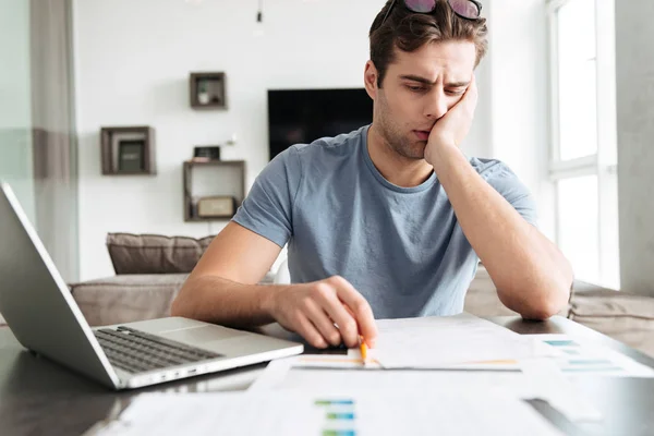 Hombre cansado concentrado trabajando con papeles en casa — Foto de Stock