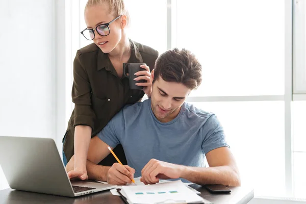 Young busy couple working with laptop at home