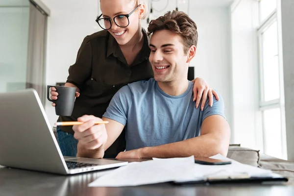 Smiling couple using laptop computer at home — Stock Photo, Image