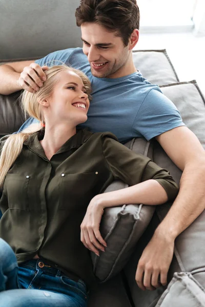 Щасливі коханці лежать на дивані і обіймаються у вітальні — стокове фото