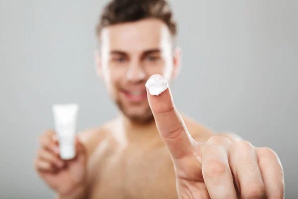 Retrato de belleza de un hombre medio desnudo aplicando crema facial — Foto de Stock