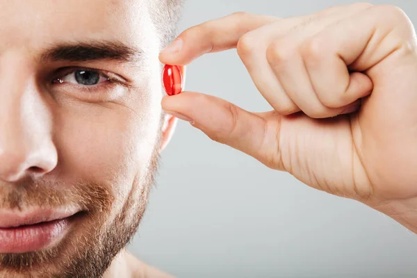 Close up retrato de um homem sorridente segurando cápsula vermelha — Fotografia de Stock