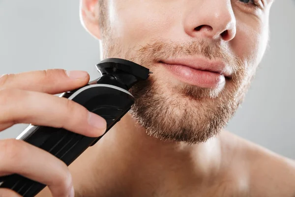 Close up shot of handsome man smiling while shaving his face wit — Stock Photo, Image