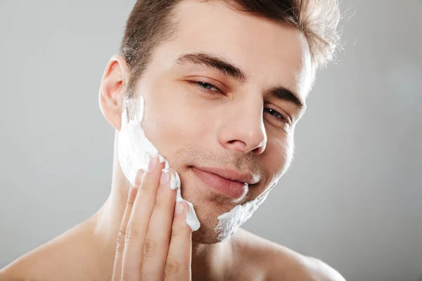 Close up retrato de um homem sorridente aplicando espuma de barbear — Fotografia de Stock