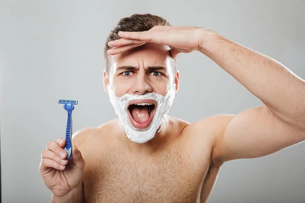 Expresiones faciales divertidas de hombre sin afeitar haciendo procedimiento matutino —  Fotos de Stock