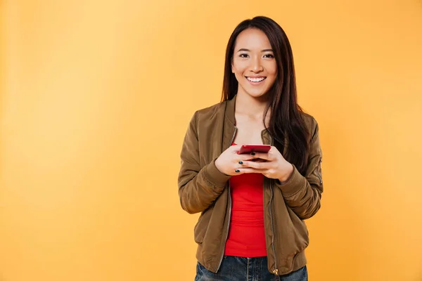 Retrato de una joven sonriente asiática sosteniendo teléfono móvil — Foto de Stock