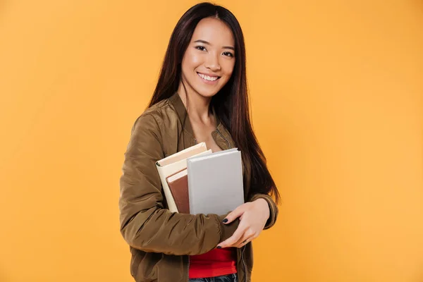 Retrato de una sonriente chica asiática sosteniendo libros — Foto de Stock