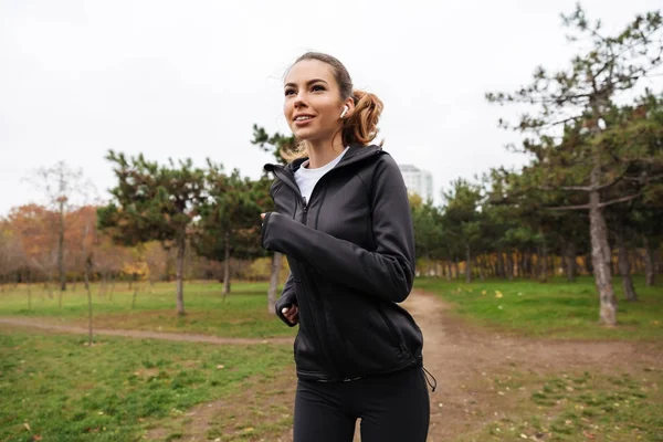 Retrato de una chica de fitness sonriente en auriculares corriendo — Foto de Stock