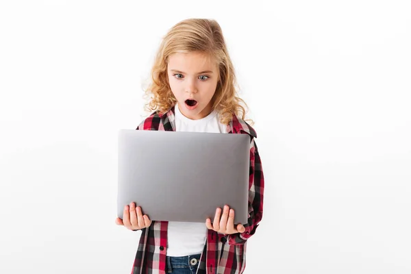 Portrait of an astonished little girl looking at laptop — Stock Photo, Image