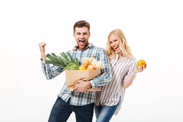 Portrait of a cheerful couple holding paper shopping bag