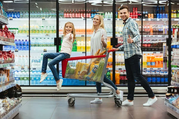 Boldog fiatal család, egy gyermek ül egy kosár — Stock Fotó