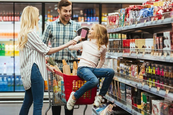 Alegre niña sentada en un carrito de compras — Foto de Stock