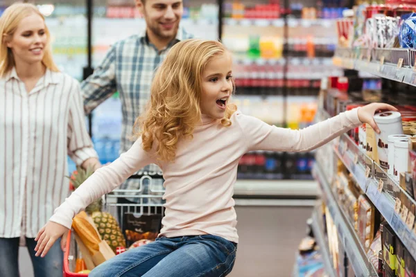 Glückliches kleines Mädchen auf einem Einkaufswagen sitzend — Stockfoto