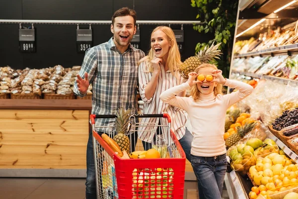 Счастливая семья с ребенком покупает еду в продуктовом магазине — стоковое фото