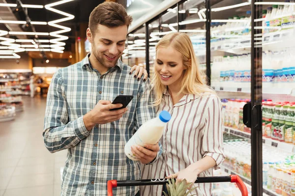 Pareja en supermercado leyendo lista de compras —  Fotos de Stock