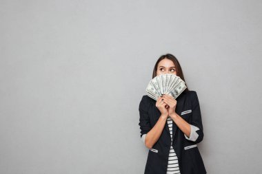 Parayı saklamanın ve uzağa bakarak gülümseyen iş kadını