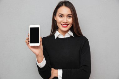 Gülümseyen iş elbiseleri boş smartphone ekran gösteren Asyalı kadın