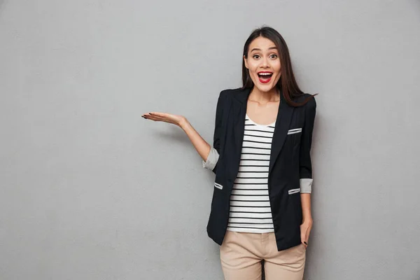 Surpreendido feliz asiático mulher de negócios segurando copyspace na palma da mão — Fotografia de Stock