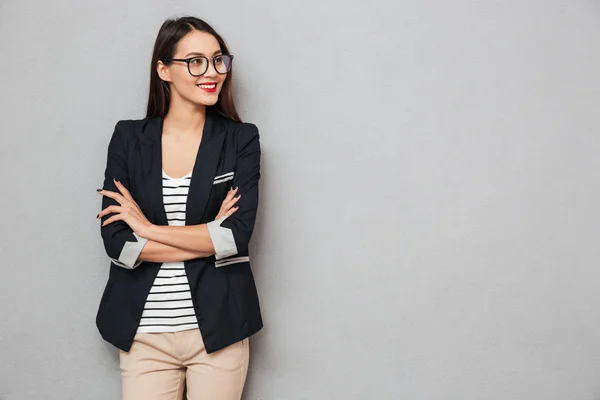 Mujer de negocios sonriente en gafas con los brazos cruzados mirando hacia otro lado — Foto de Stock