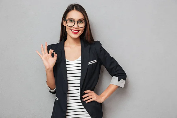 Усміхнена азіатська бізнес-леді в окулярах з рукою на стегні — стокове фото