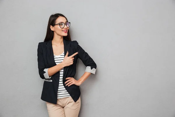 Улыбающаяся азиатская деловая женщина в очках с рукой на бедре — стоковое фото