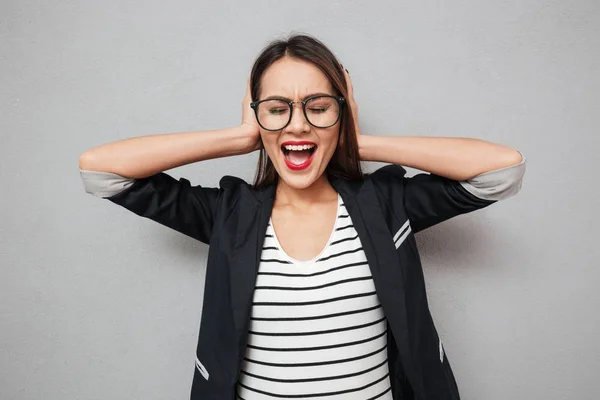 Confundido asiático mujer de negocios en gafas gritando y cubriendo oídos — Foto de Stock