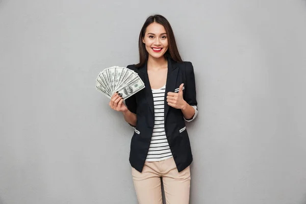 Приятно азиатская деловая женщина с деньгами и показывая большой палец вверх — стоковое фото