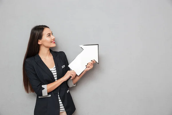 Leende affärskvinna pekar med papper pil och letar upp — Stockfoto