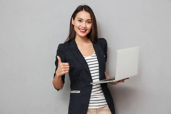 Geschäftsfrau hält Laptop in der Hand und zeigt Daumen hoch — Stockfoto