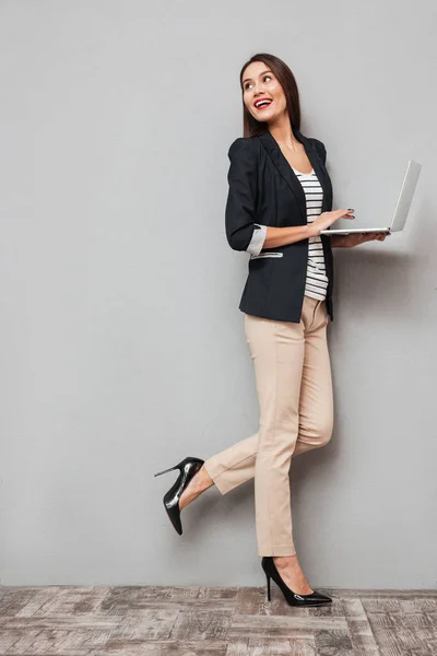 Imagem de comprimento total de mulher de negócios feliz segurando computador portátil — Fotografia de Stock