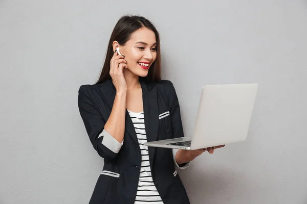 Sorrindo asiático mulher de negócios em fones de ouvido usando computador portátil — Fotografia de Stock
