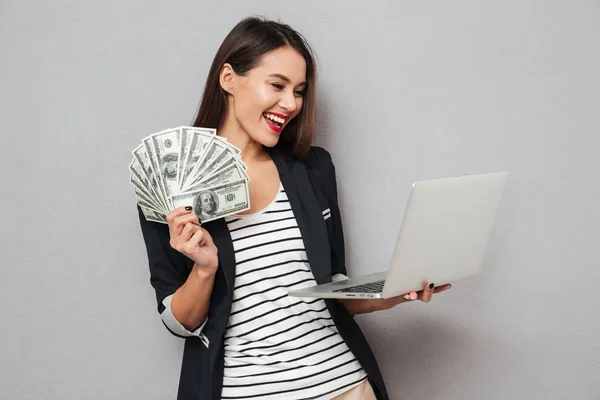 Happy asian business woman holding money and laptop computer — Stock Photo, Image