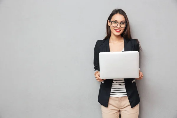 Усміхнена азіатська бізнес-леді в окулярах тримає ноутбук комп'ютера — стокове фото