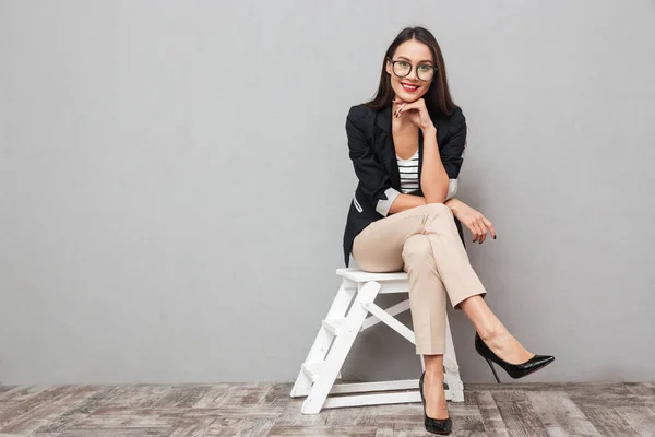 Lachende Aziatische zakenvrouw in brillen zit op stoel — Stockfoto