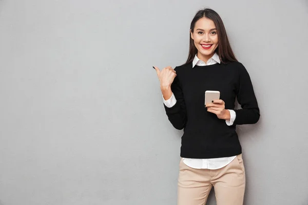 Souriant asiatique femme en vêtements d'affaires tenant smartphone — Photo