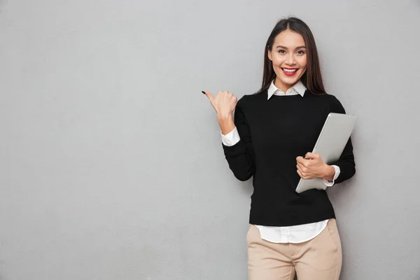 Smiling asian woman in business clothes holding laptop computer — Stock Photo, Image