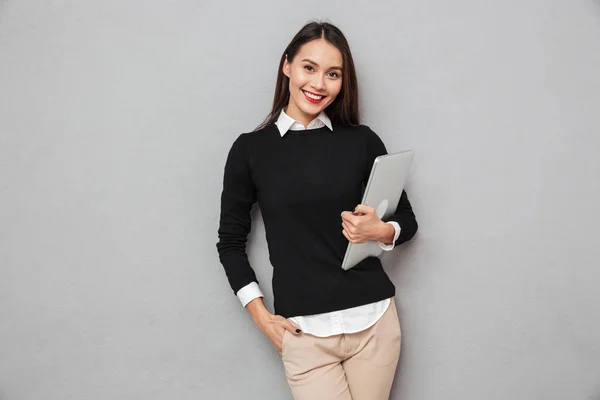 Sonriendo mujer asiática en ropa de negocios celebración de ordenador portátil — Foto de Stock