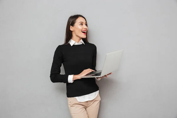 Смеющаяся азиатка в деловой одежде с помощью ноутбука — стоковое фото