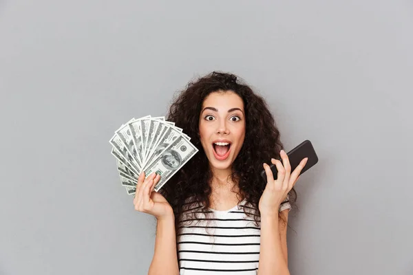 Lucky woman with curly hair holding fan of 100 dollar bills and — Stock Photo, Image