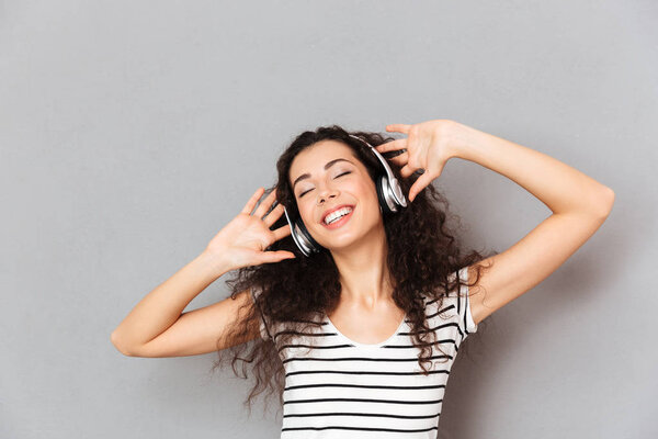 Picture of pleased young woman in striped t-shirt enjoying favou