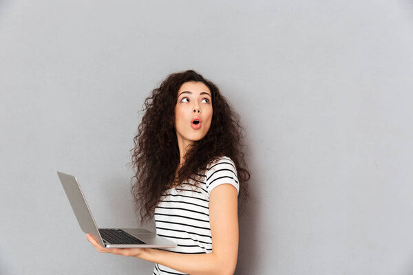 Lovely lady with curly hair posing with silver laptop being isol