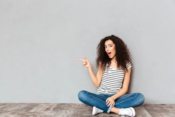 Lovely curly woman in casual clothes sitting in lotus pose on th — Stock Photo, Image