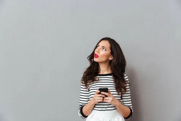 Portrait of a pensive girl holding mobile phone — Stock Photo, Image