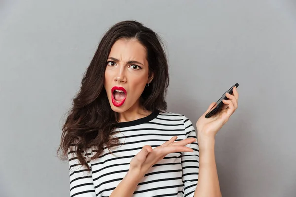 Närbild porträtt av en chockad flicka som håller mobiltelefon — Stockfoto