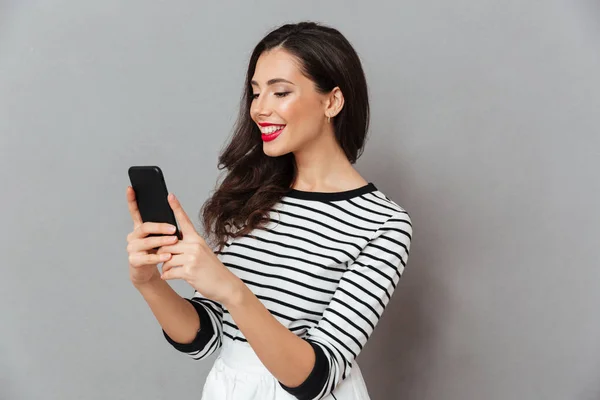 Portrait of a cheerful girl looking at mobile phone — Stock Photo, Image