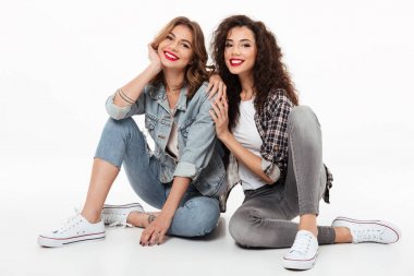 Katta birlikte oturan iki gülümseyen kız