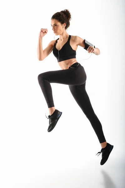 Imagem de comprimento total de Concentrado encaracolado morena fitness mulher correndo — Fotografia de Stock