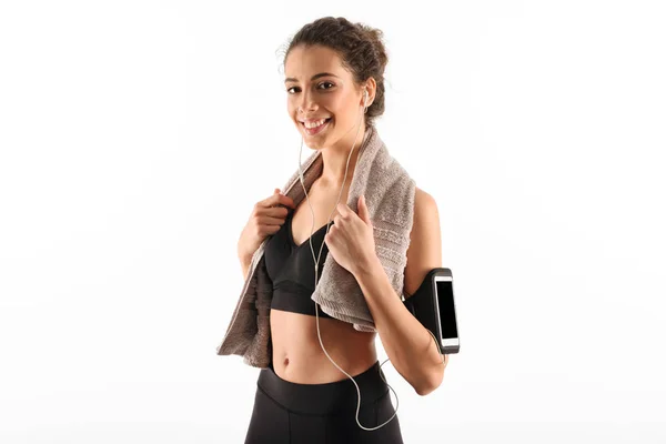 Feliz encaracolado morena fitness mulher com toalha ouvir música — Fotografia de Stock