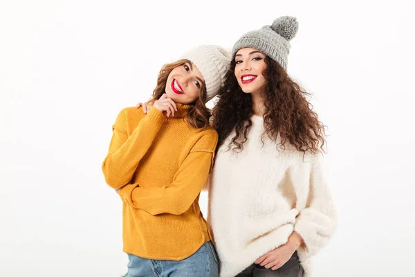 Twee lachende meisjes in truien en hoeden poseren samen — Stockfoto