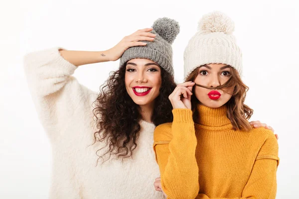 Duas meninas bonitas em camisolas e chapéus posando juntos — Fotografia de Stock
